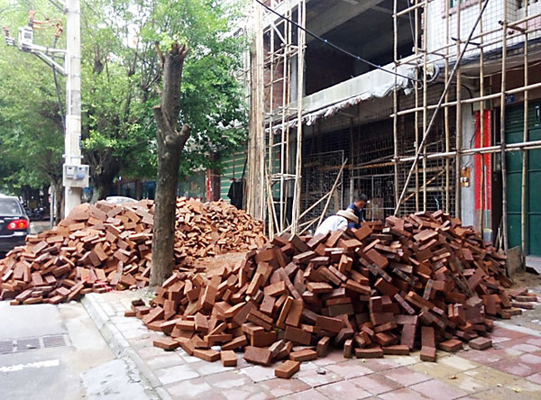 建設路建筑材料亂堆放，人行道變“攔路虎”